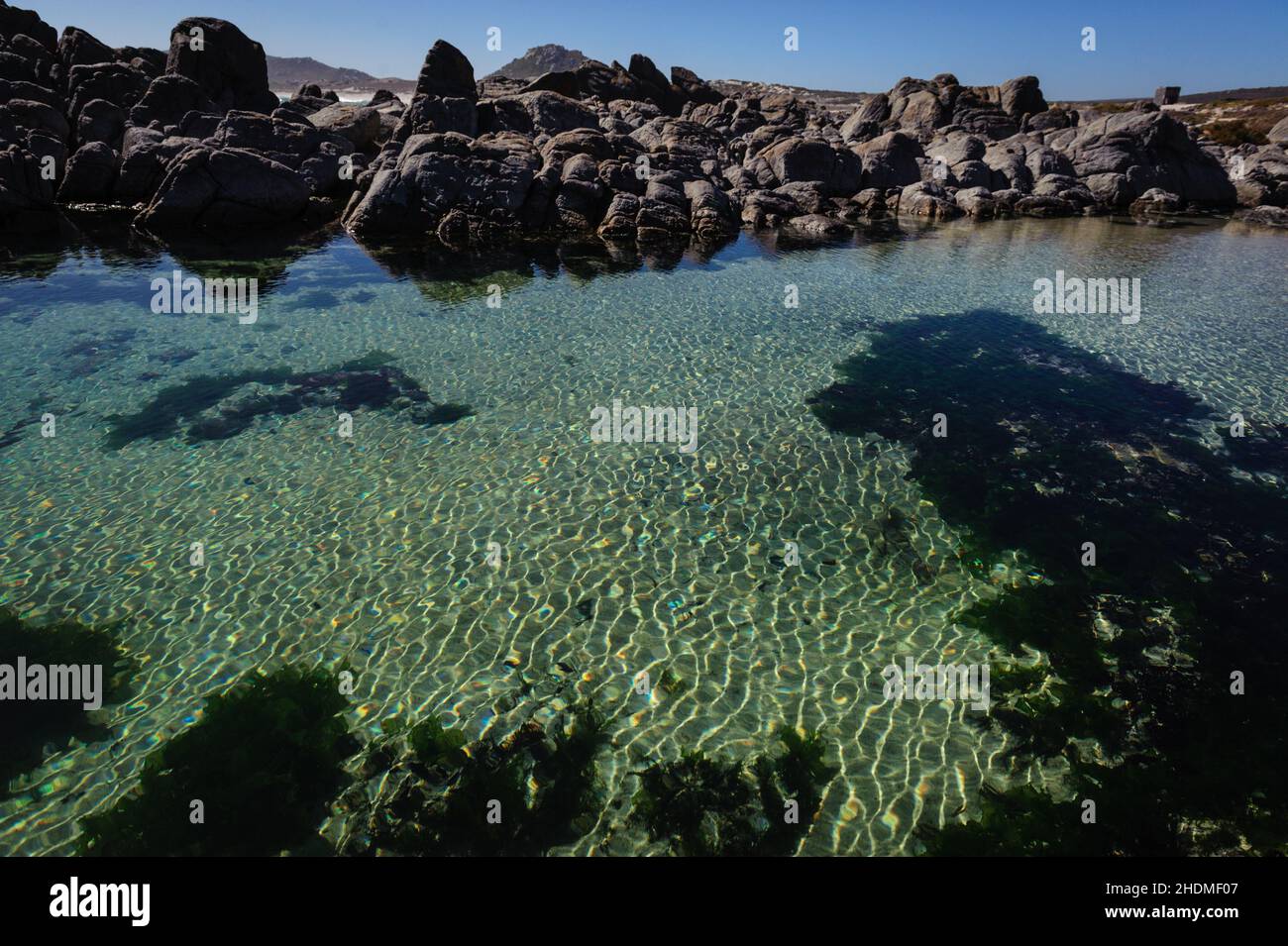 Ein natürlicher Felsenpool an der Westküste Südafrikas. Die Schönheit und der Charakter der Küste werden durch das raue und zerklüftete Gelände zum Ausdruck gebracht Stockfoto