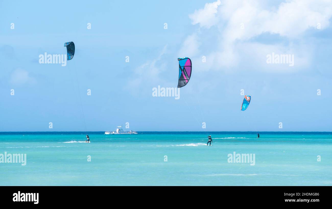 Kiteboarder reiten im Wind auf dem türkisfarbenen Wasser des Karibischen Meeres vor dem Hadicurari Beach in Aruba. Stockfoto