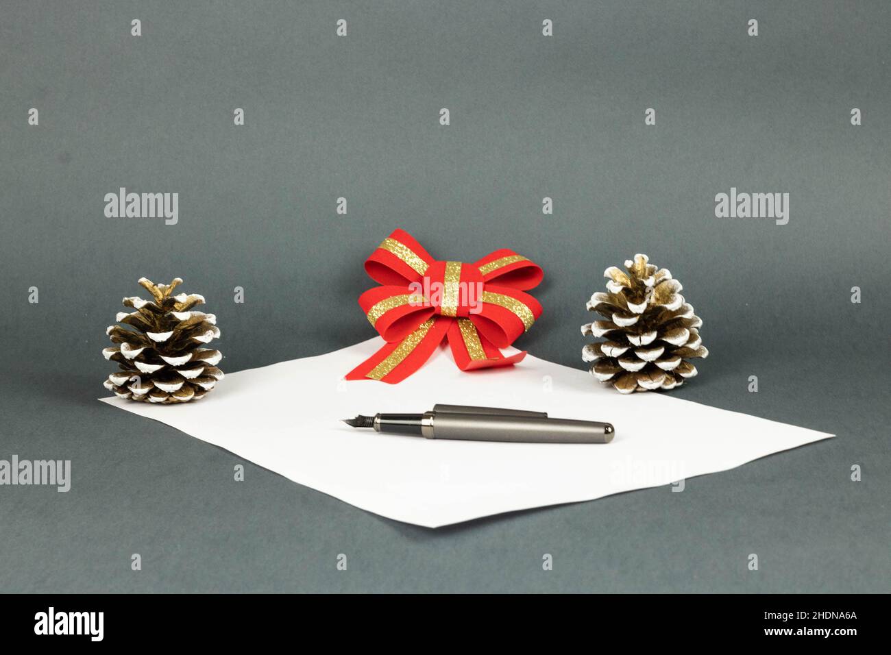 Nahaufnahme eines Stiftes, der auf einem weißen Stück Papier liegt, mit einem verschwommenen Hintergrund aus rotem Bogen und Eicheln Stockfoto