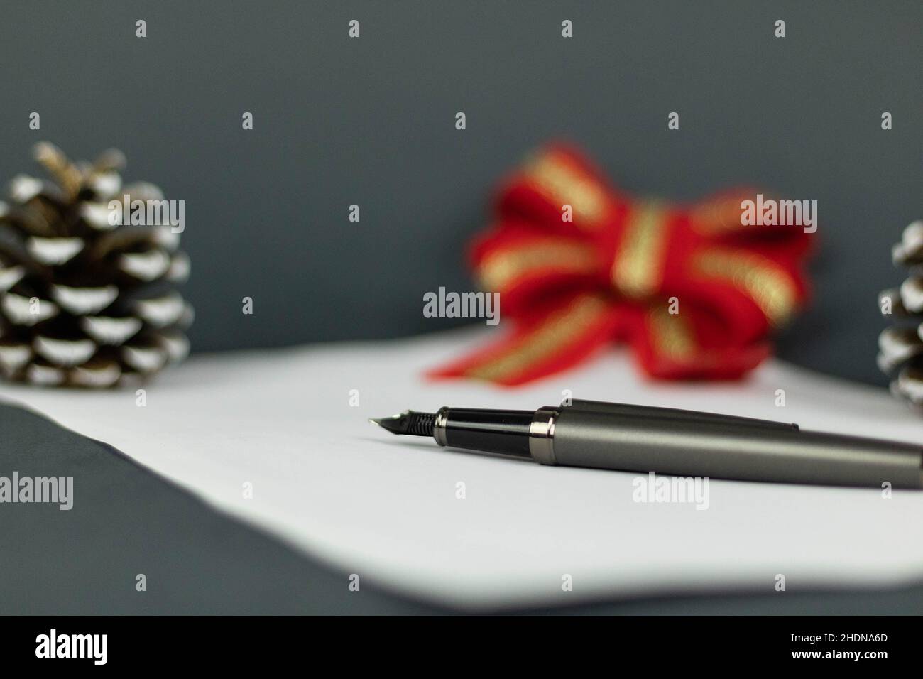 Makro eines Stifts, der auf einem weißen Stück Papier mit einem verschwommenen Hintergrund aus rotem Bogen und Eichel liegt Stockfoto