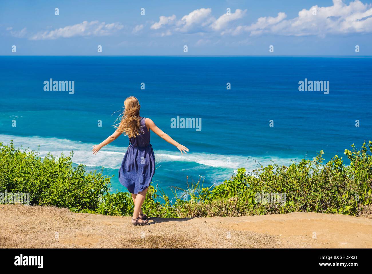 Junge Frau Tourist auf einer Klippe über dem Strand. Leere Paradies Strand, blaues Meer Wellen in Insel Bali, Indonesien. Von Suluban und Nyang Nyang Ort Stockfoto