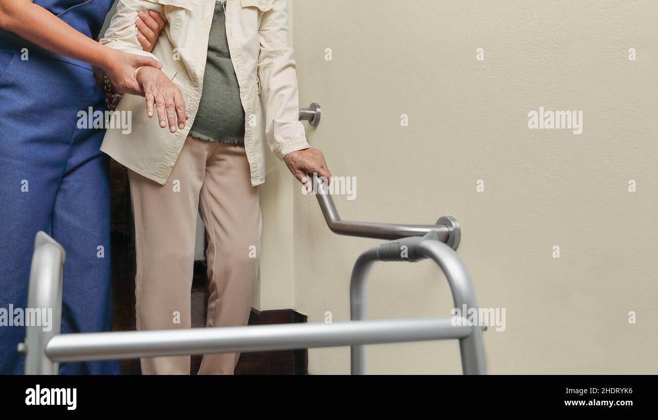 Ältere Frau, die mit der Pflegekraft am Handlauf festhält Stockfoto