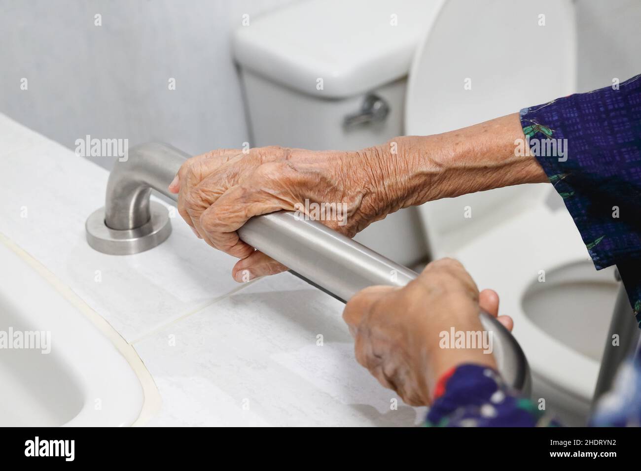 Ältere Frau, die im Badezimmer am Handlauf festhält Stockfoto