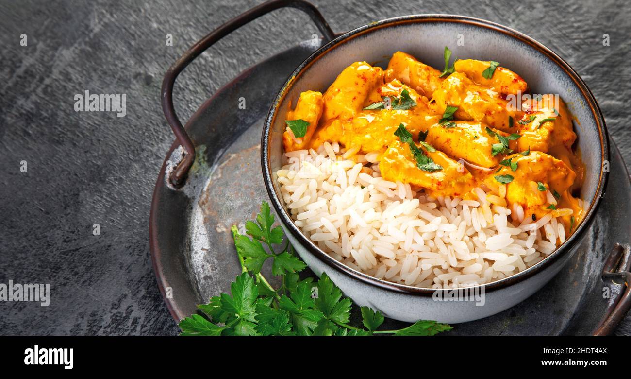 Indisches Butterhuhn-Curry mit Basmati-Reis auf dunklem Hintergrund. Traditionelles hausgemachtes Lebensmittelkonzept. Platz kopieren Stockfoto