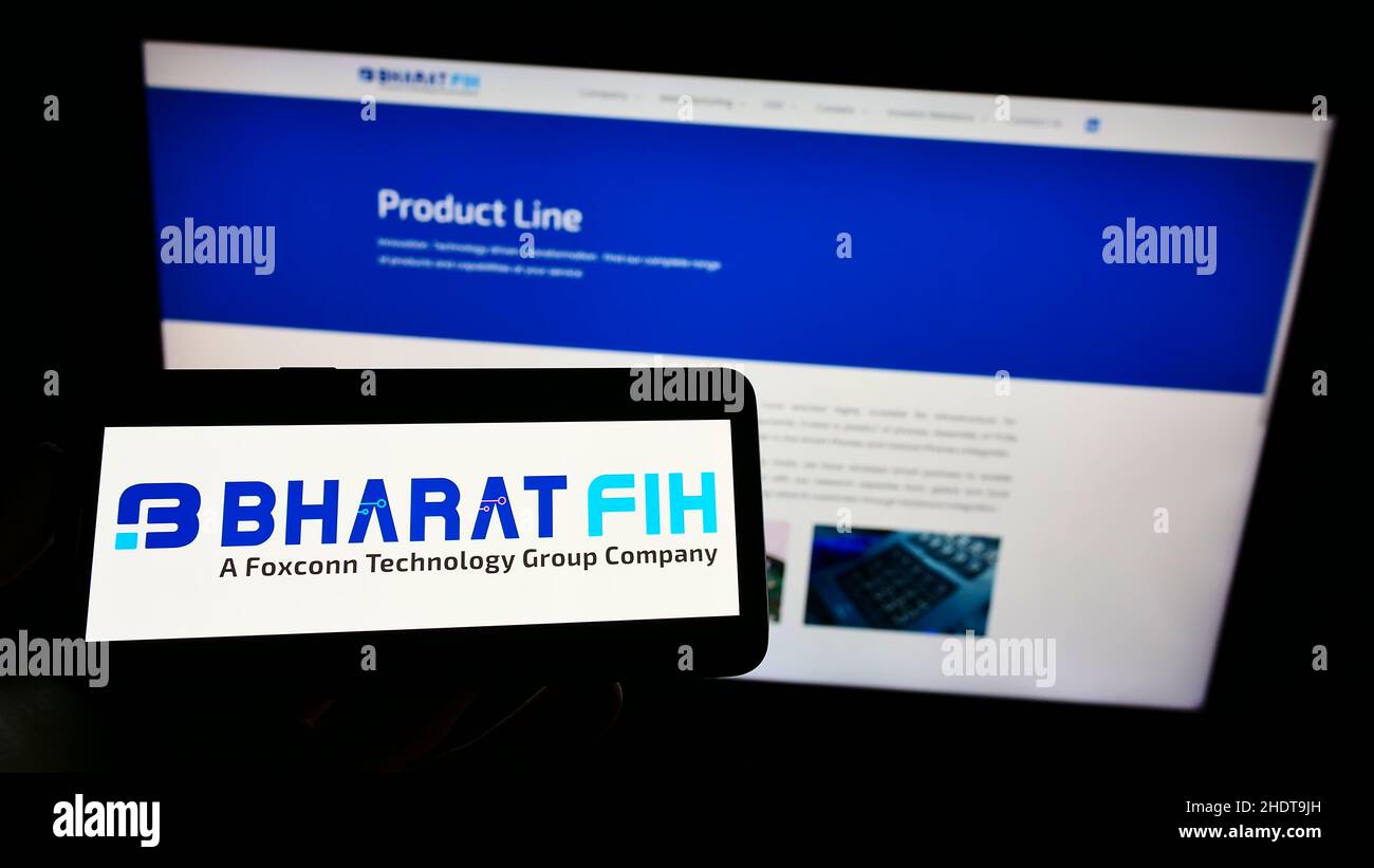 Person, die Mobiltelefon mit dem Logo des indischen Elektronikunternehmens Bharat FIH Private Ltd auf dem Bildschirm vor der Webseite hält. Konzentrieren Sie sich auf die Telefonanzeige. Stockfoto
