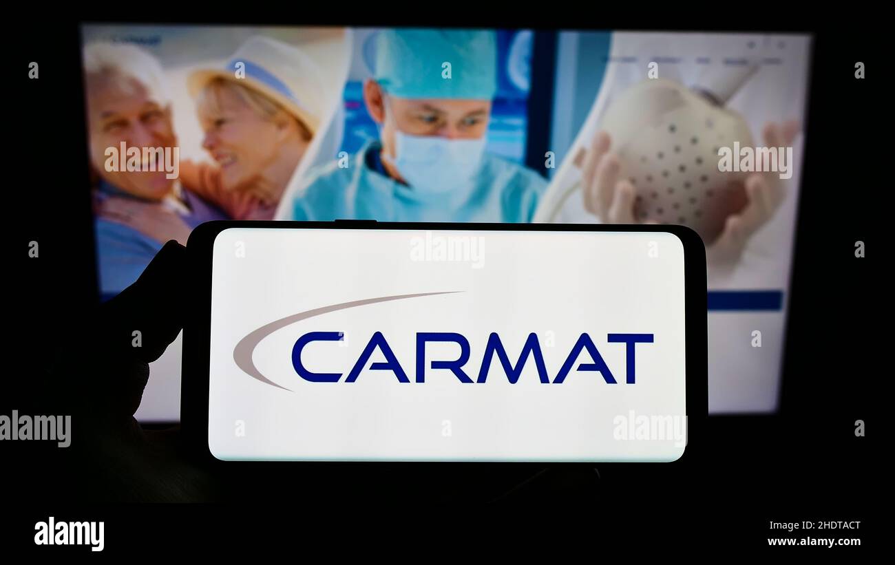 Person, die das Smartphone mit dem Logo des französischen Medizintechnik-Unternehmens Carmat SA auf dem Bildschirm vor der Website hält. Konzentrieren Sie sich auf die Telefonanzeige. Stockfoto