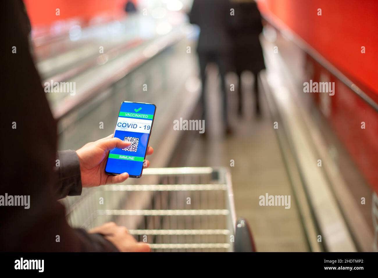 Mann mit Covid Zertifikat auf dem Smartphone, die ihm erlauben, Waren zu kaufen Stockfoto
