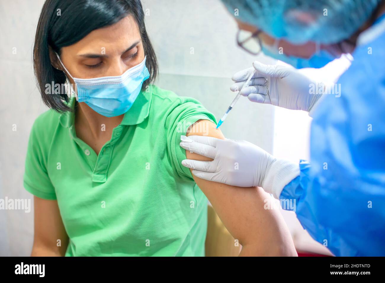 Impfung, Impfkampagne, Konzept zur Prävention von Krankheiten. Junge Frau in medizinischer Gesichtsmaske, die Covid-19-Impfstoff in der Arztpraxis erhält. Für Stockfoto