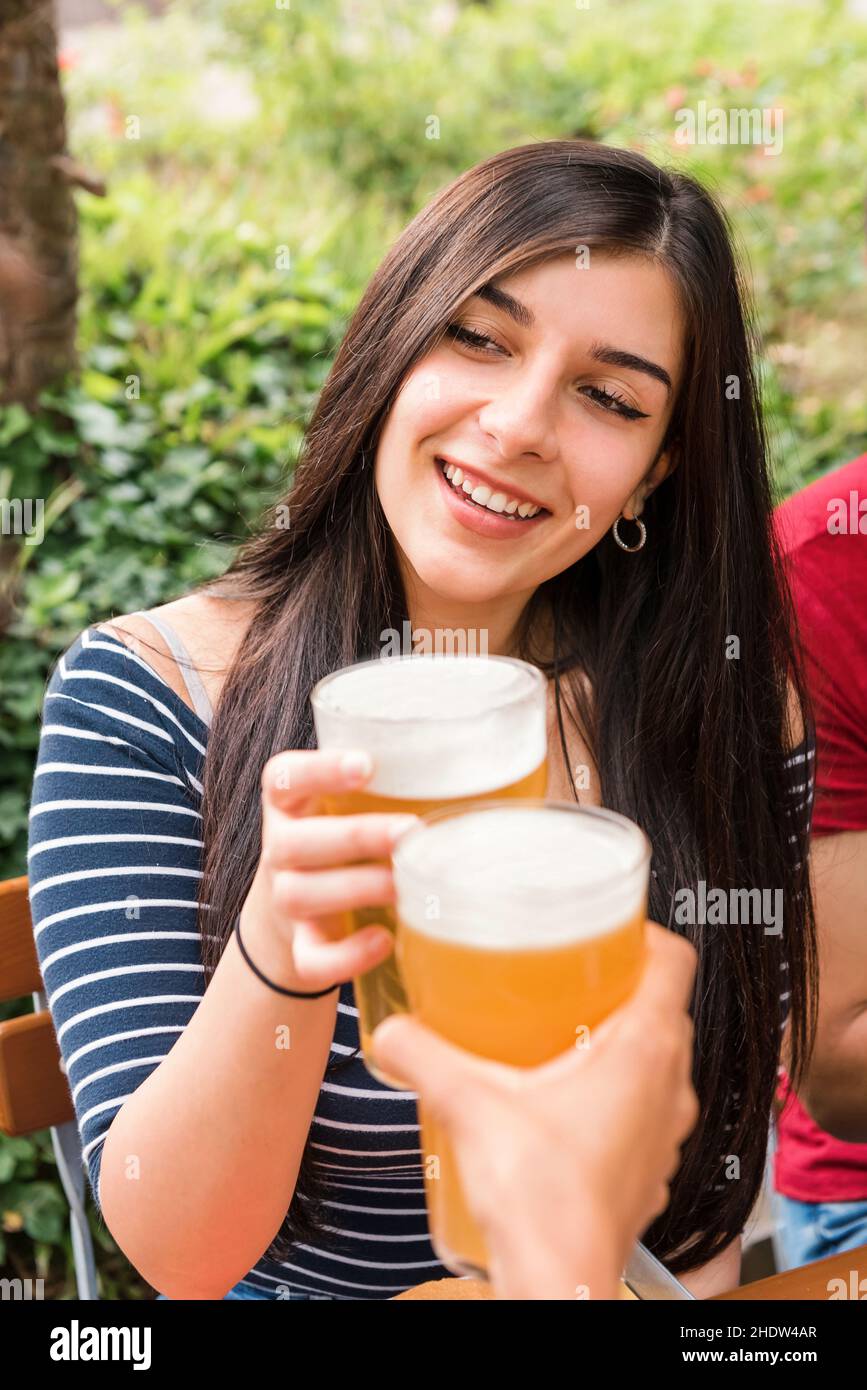 Fröhliche weibliche Klirren Glas erfrischendes Bier mit unkenntlichen Freunden während der Wiedervereinigung während Picknick im Park feiern Stockfoto