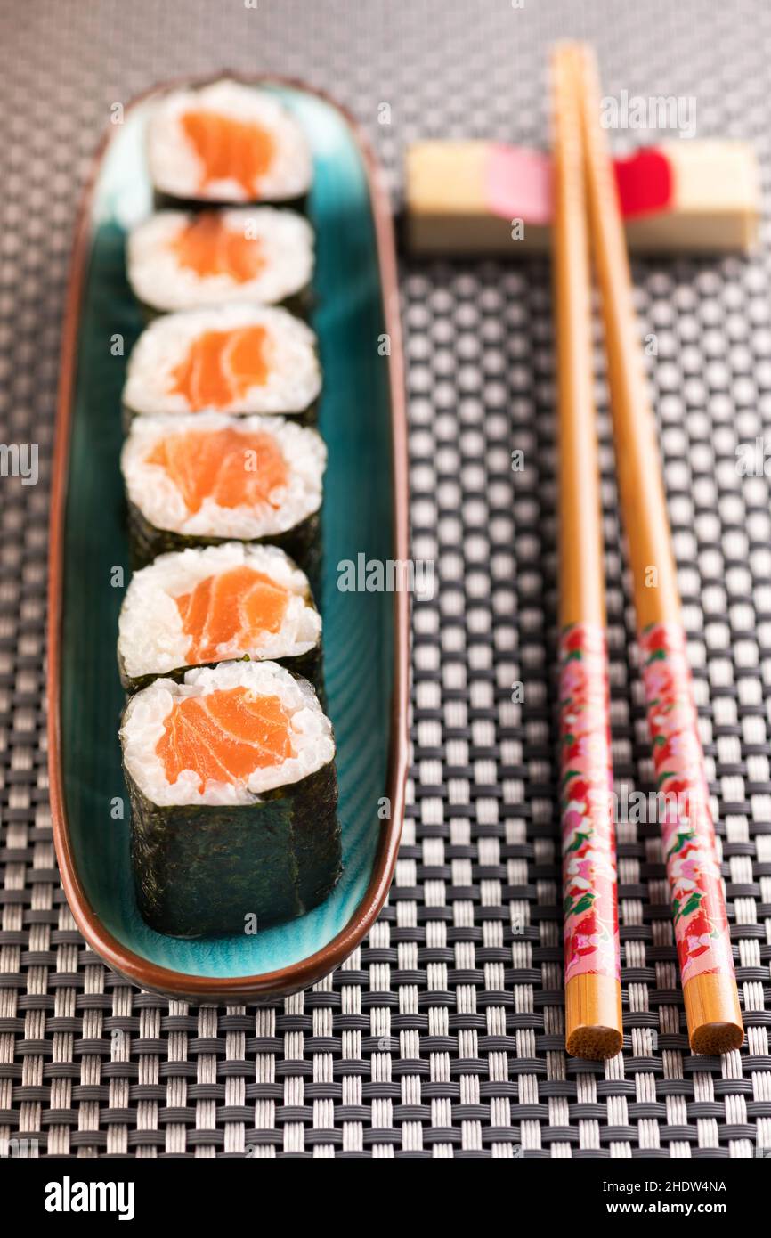 Oben von frischen Hosomaki-Sushi-Rollen auf dem Teller, die neben Essstäbchen auf dem Tisch platziert wurden Stockfoto