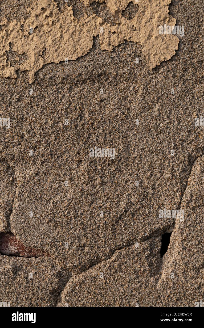 Alte Mauer mit zerbröckelndem und ruinierten gelben Putz, senkrechte Ansicht Stockfoto
