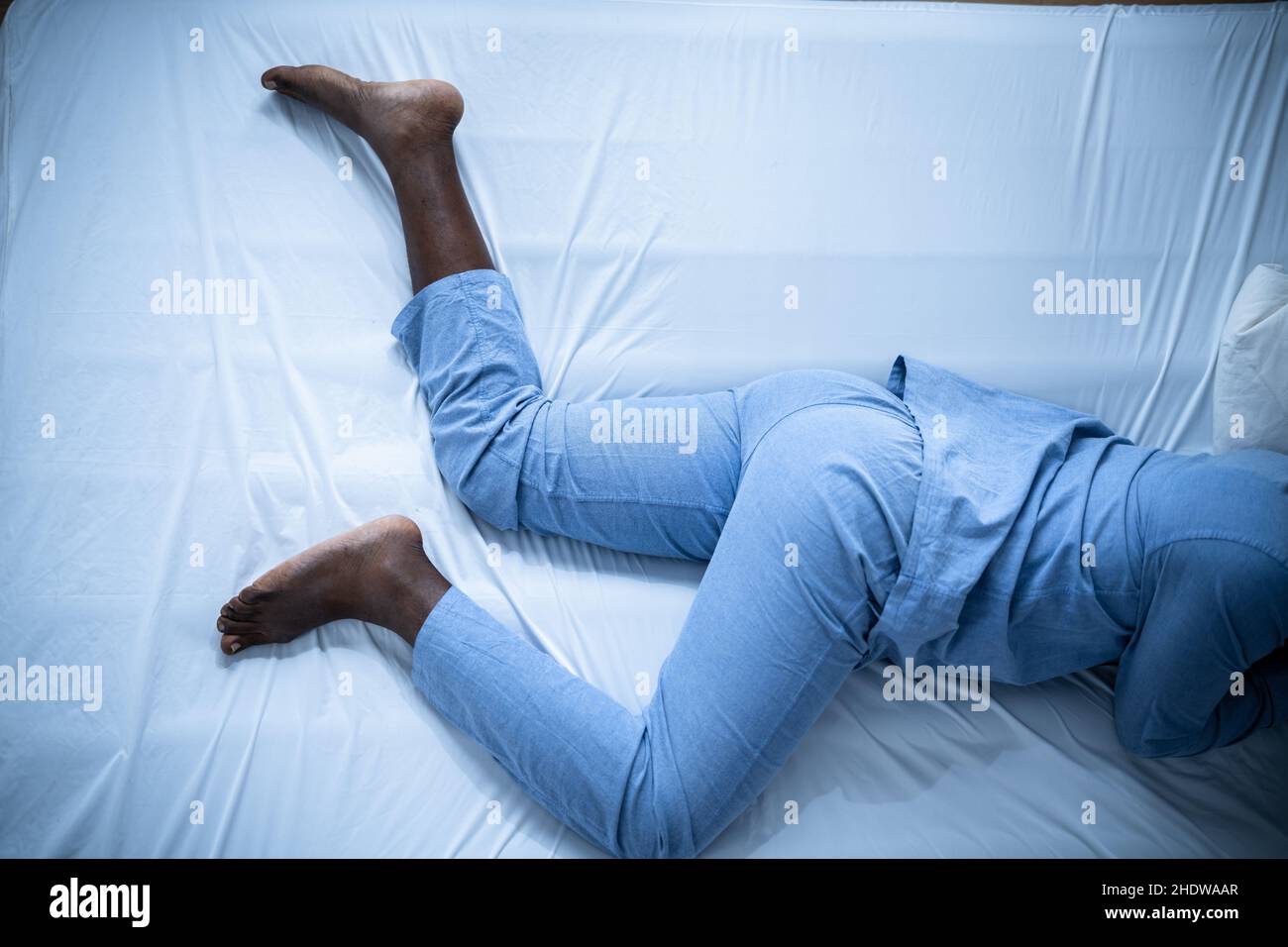 Afroamerikanischer Mann mit RLS - Restless Legs Syndrom. Schlafen Im Bett Stockfoto