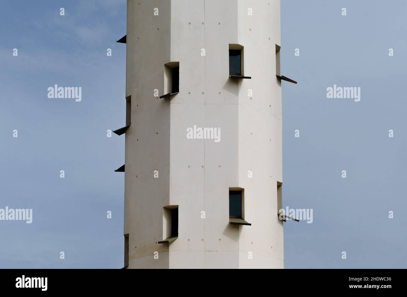 Nahaufnahme eines alten und weißen Leuchtturms. Vorderansicht eines hohen Turms mit vielen Fenstern. Funktionstümvoller Leuchtturm an einem Strand in tarragona, spanien Stockfoto