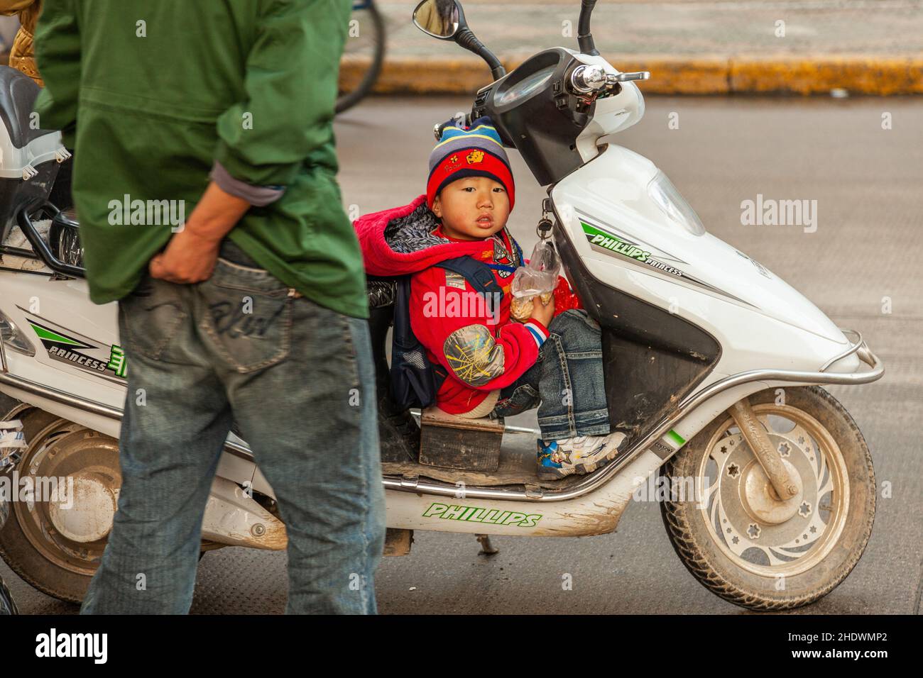 Kleiner Junge, der vor einem Roller sitzt. Jiashan, China Stockfoto