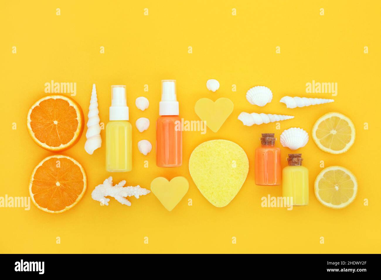 Natürliche frische Zitrusfrüchte aus Orange und Zitrone für die Hautpflegebehandlung mit Feuchtigkeitscreme, Lotion, Seife, Schwamm und Muscheln auf Gelb. Stockfoto