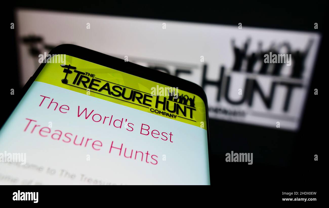 Mobiltelefon mit Website des britischen Unternehmens The Treasure Hunt Company (Brighton) auf dem Bildschirm vor dem Logo. Konzentrieren Sie sich auf die obere linke Seite des Telefondisplays. Stockfoto
