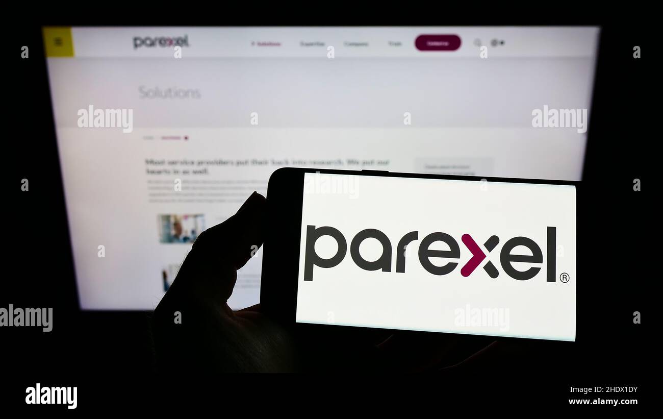 Person, die das Smartphone mit dem Logo der US-amerikanischen Parexel International Corporation auf dem Bildschirm vor der Website hält. Konzentrieren Sie sich auf die Telefonanzeige. Stockfoto