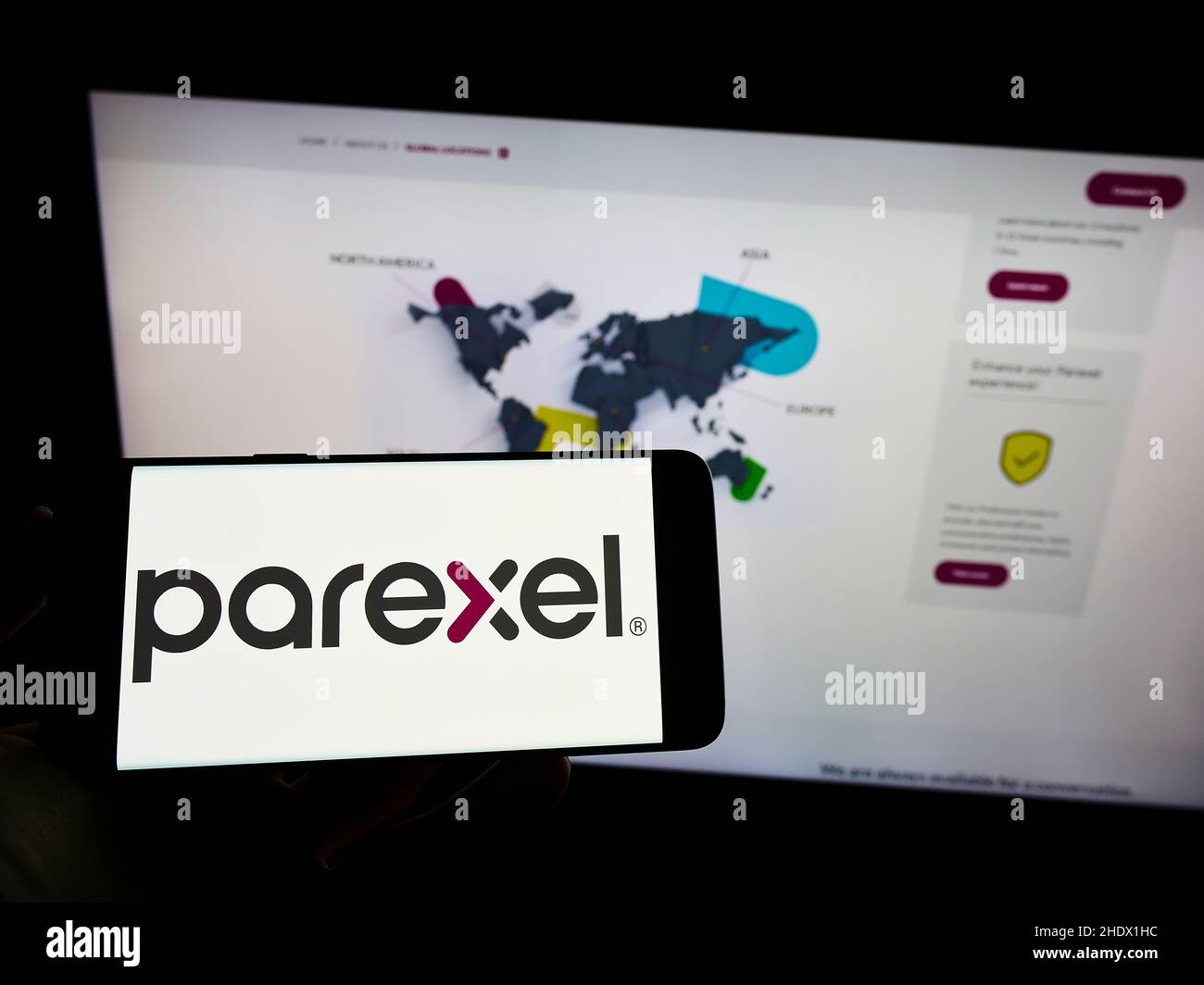 Person, die Mobiltelefon mit dem Logo der US-amerikanischen Parexel International Corporation auf dem Bildschirm vor der Business-Webseite hält. Konzentrieren Sie sich auf die Telefonanzeige. Stockfoto