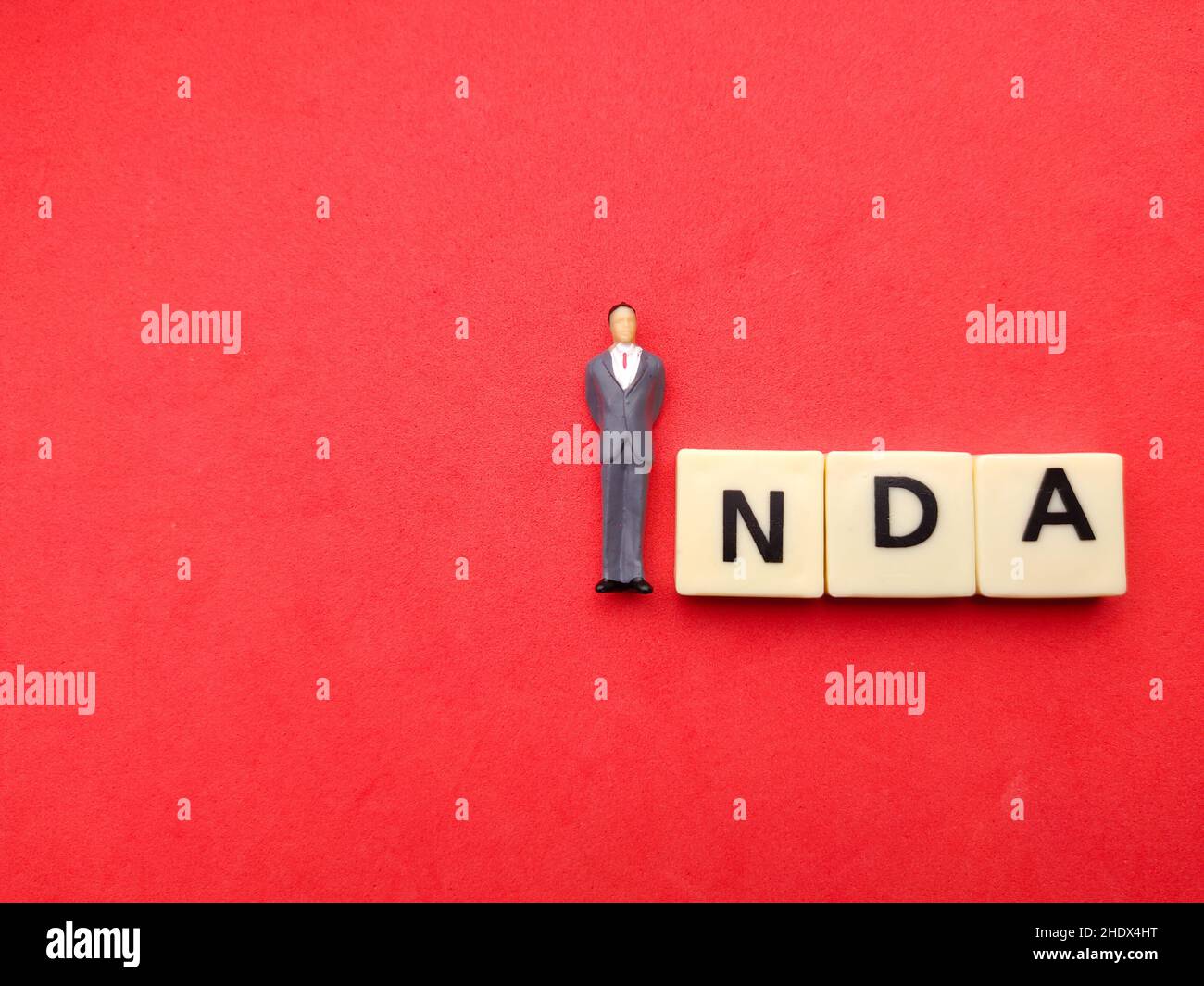 Miniatur-Menschen mit Wort NDA auf rotem Hintergrund. Stockfoto