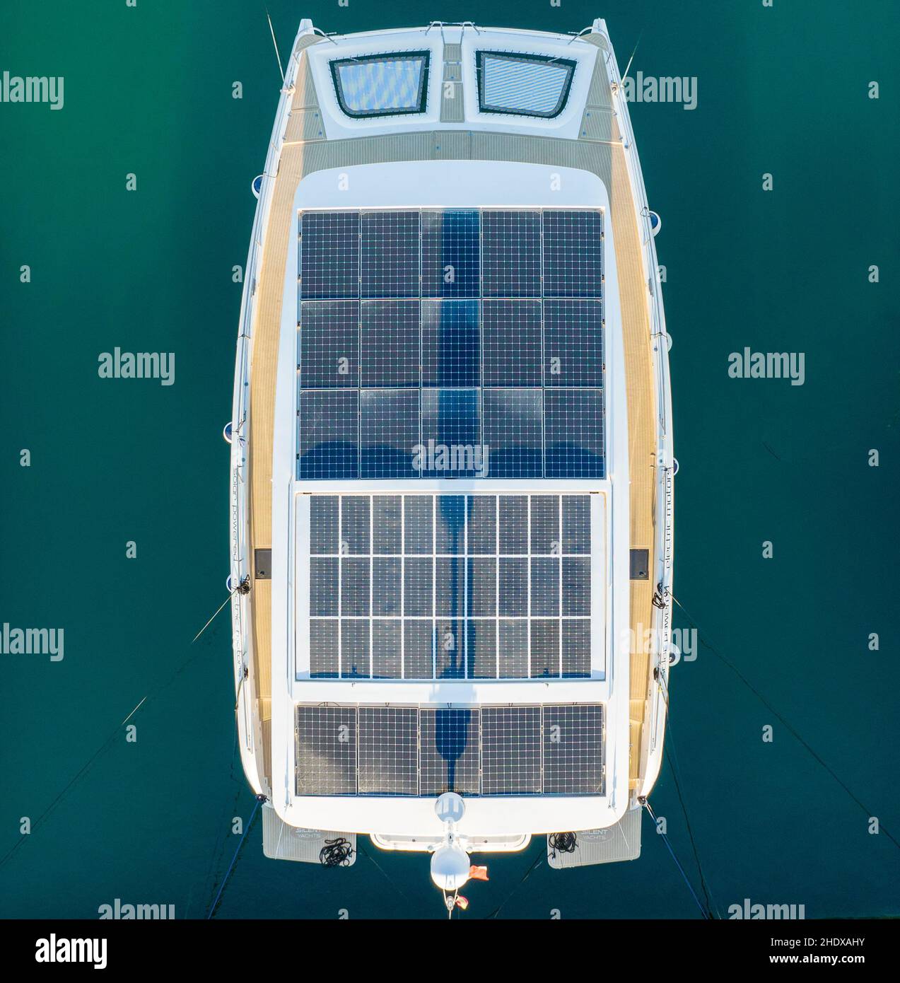 Blick von oben auf das moderne Motorboot mit Photovoltaikpaneelen auf dem Dach, das auf türkisfarbenem Meerwasser festgemacht ist Stockfoto