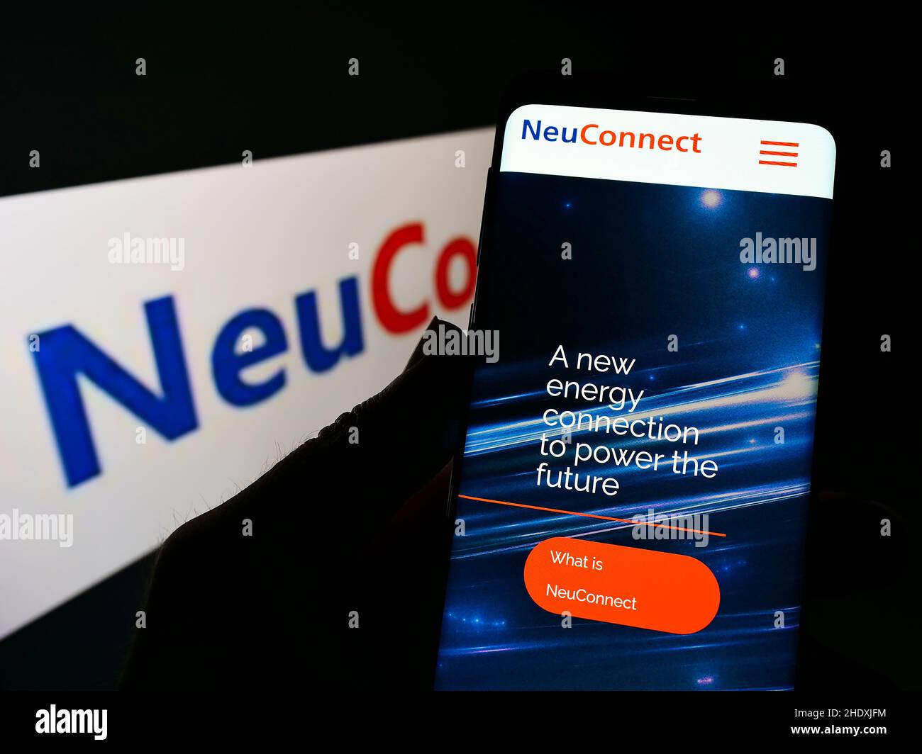 Person, die Mobiltelefon mit Website des Stromkabelprojekts NeuConnect Interconnector auf dem Bildschirm mit Logo hält. Konzentrieren Sie sich auf die Mitte des Telefondisplays. Stockfoto