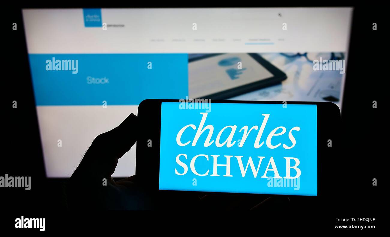 Person, die ein Smartphone mit dem Logo des US-Finanzunternehmens The Charles Schwab Corporation auf dem Bildschirm vor der Website hält. Konzentrieren Sie sich auf die Telefonanzeige. Stockfoto