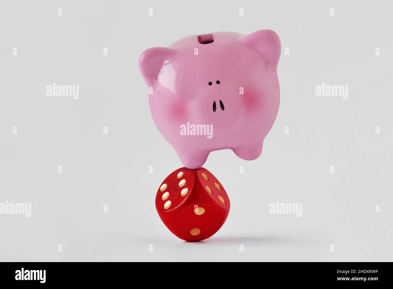 Sparschwein steht auf roten Würfeln ausgeglichen - Konzept der Wirtschaft und des finanziellen Risikos Stockfoto