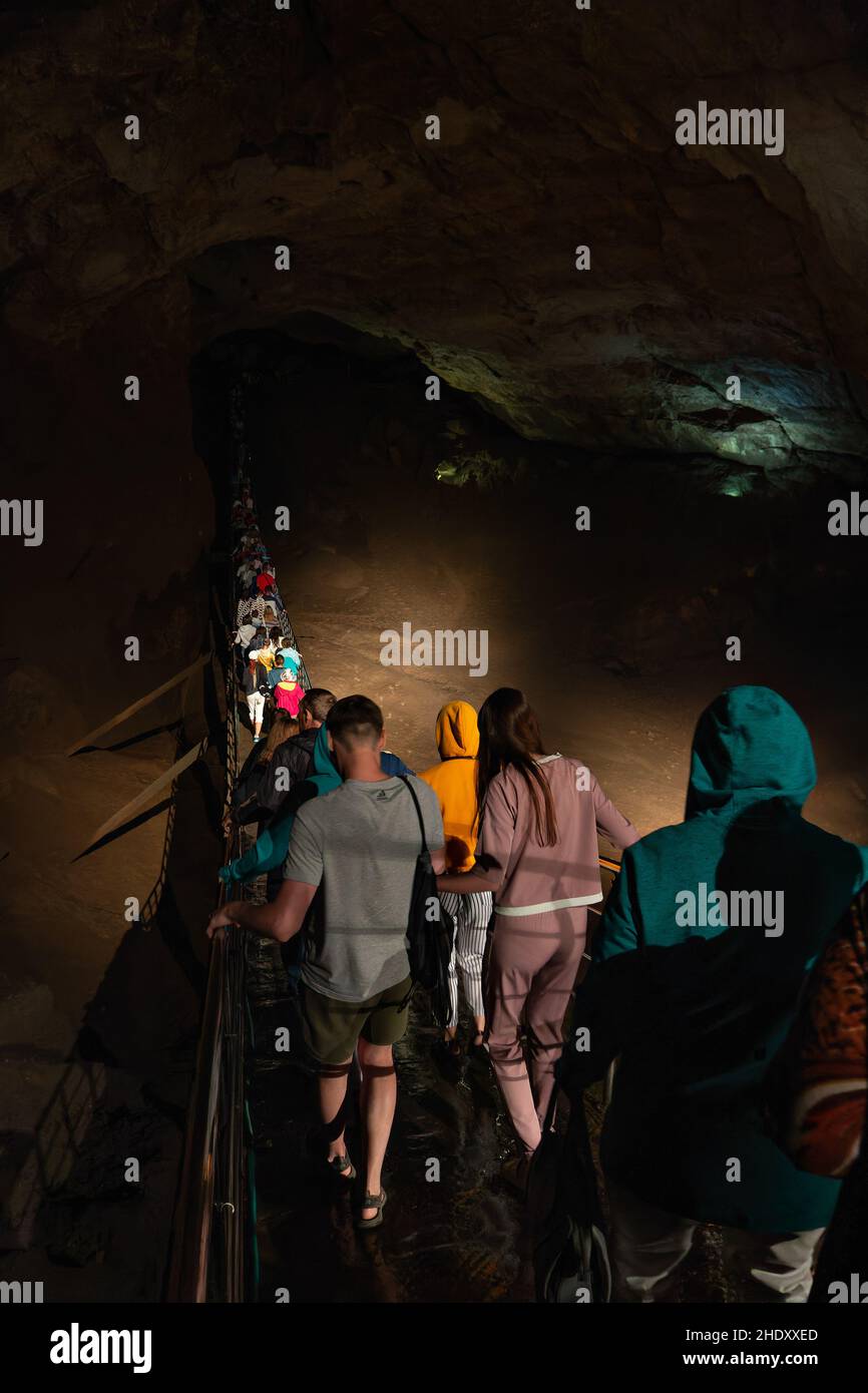 5. Juli 2018 New Athos, Abchasien: Eine Gruppe von Touristen geht über die Hängebrücke in einer riesigen Höhle. Ausflug für Touristen. Redaktionelles Bild Stockfoto