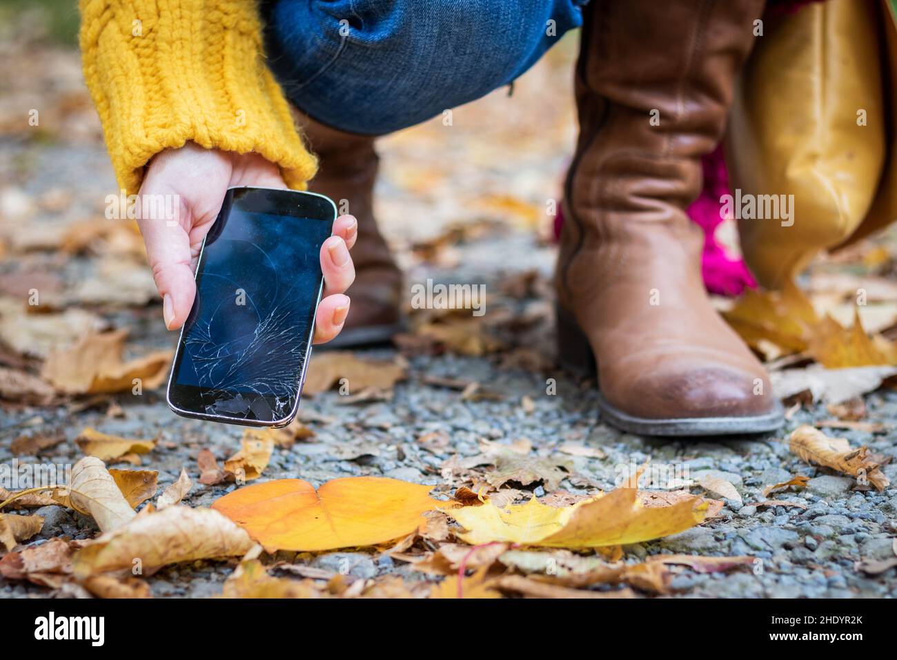 Frau, die ein beschädigtes Smartphone mit gesprungenem Touchscreen in die Hand nimmt. Defektes Smartphone in weiblicher Hand auf der Straße. Stockfoto Frau, die ein beschädigtes Smartphone mit gesprungenem Touchscreen in die Hand nimmt. Defektes Smartphone in weiblicher Hand auf der Straße. Stockfoto