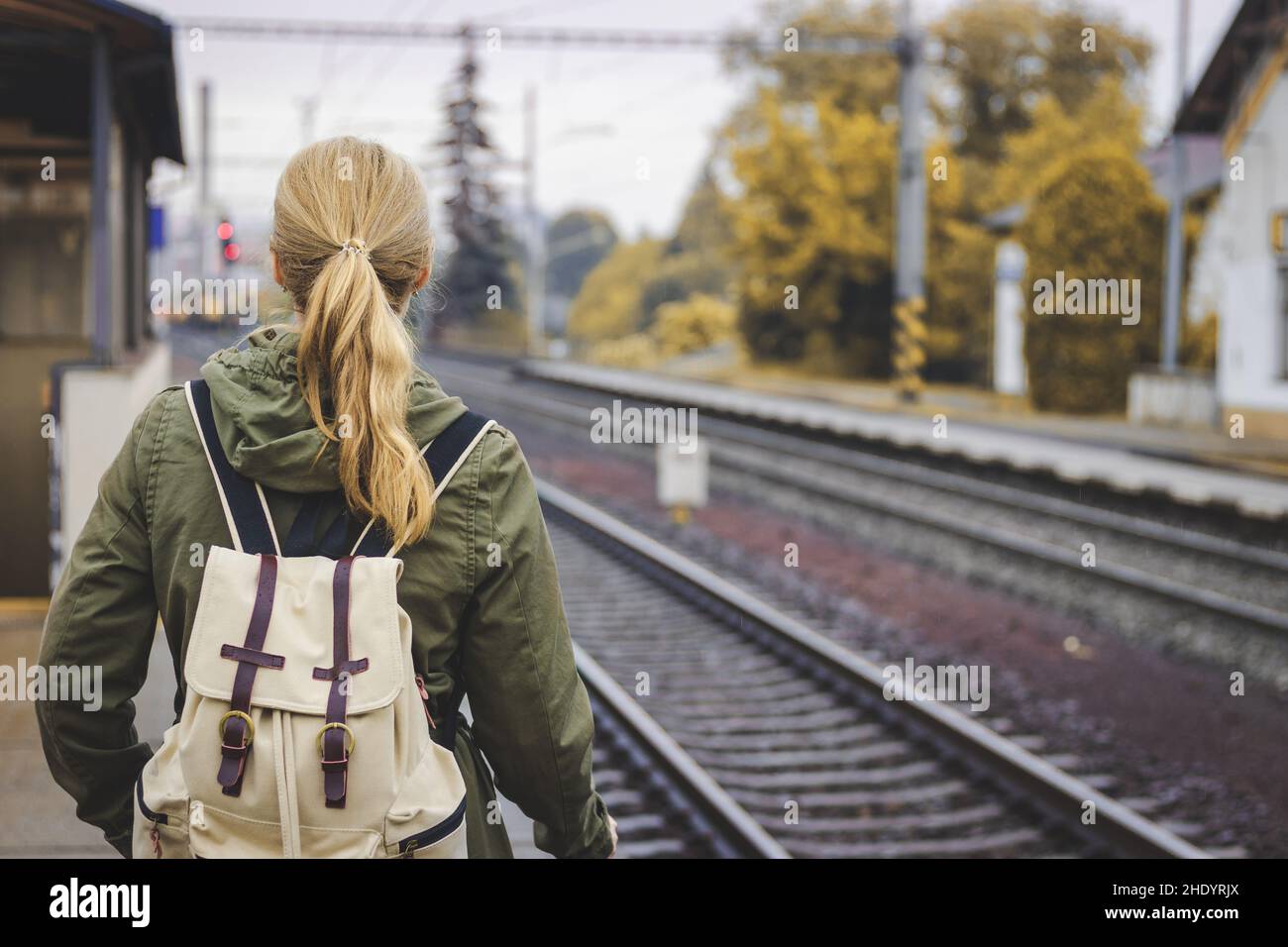 Frau mit Rucksack, die am Bahnhofsplatz steht und auf einen Zug wartet. Reisekonzept. Bahnverkehr Stockfoto