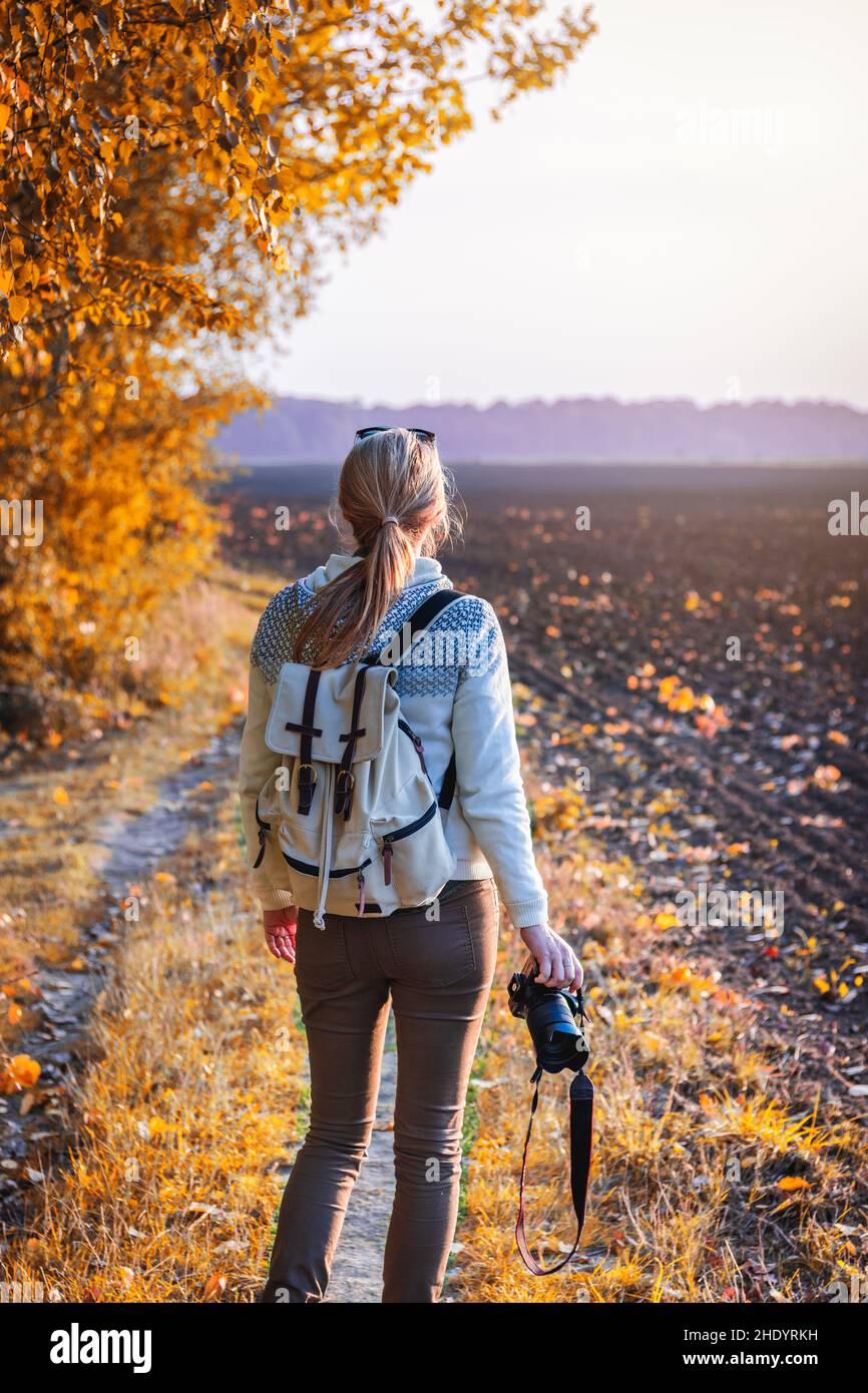 Frau mit Kamera und auf der Suche nach Komposition in der herbstlichen Natur. Wandern auf dem Land. Stockfoto