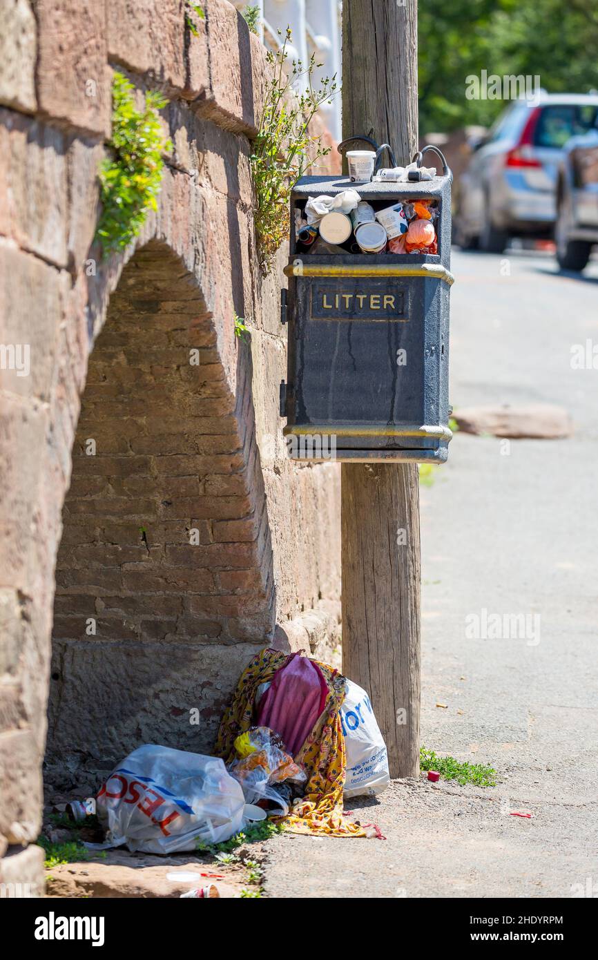 Mülltonne an einem britischen Schönheitsort, voll mit überlauftem Müll und noch mehr Müllsäcke voller Müll auf dem Boden darunter. Stockfoto