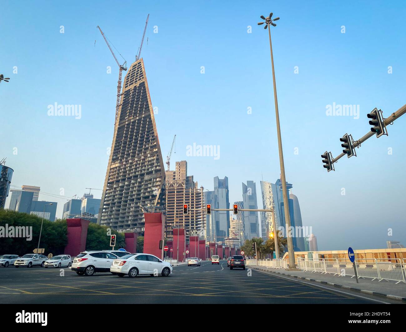 Doha, Katar – 3. Oktober 2019: Stadtbild und Skyscaper im Bau mit Autos und roter Ampel vor blauem Himmel Stockfoto