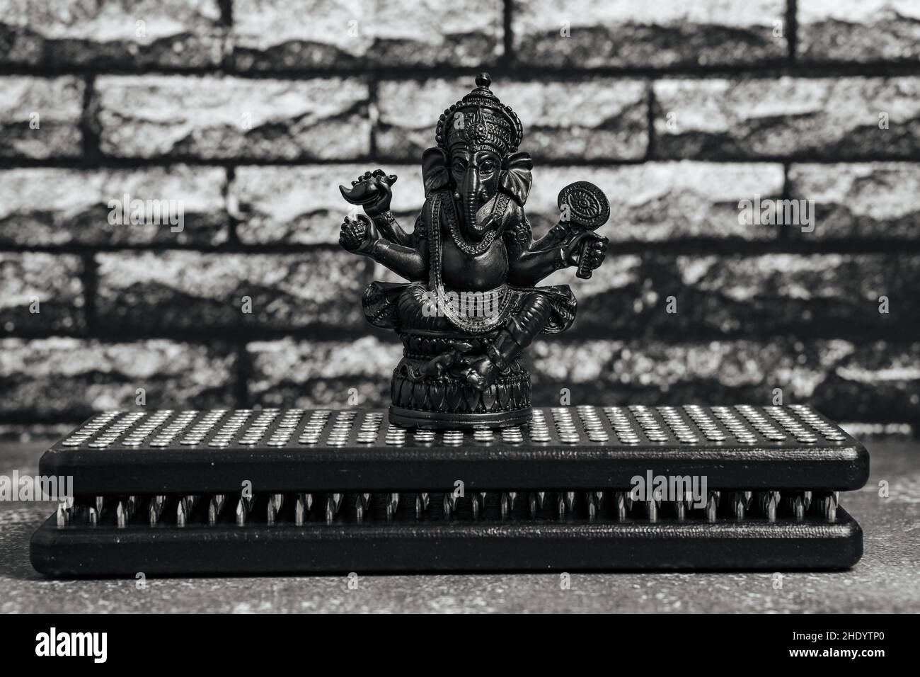 Steinstatue von Lord Ganesha, hindu-Gott.Nahaufnahme schwarze Sadhu Holzbretter mit Nägeln für Yoga, spirituelle Praktiken auf dem grauen Hintergrund und dunkle br Stockfoto