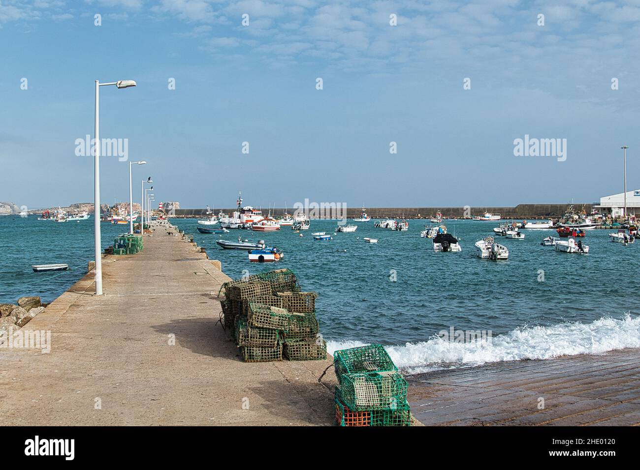 Der Fischerhafen von Sagres, Algarve, Portugal, mit einem langen Pier und geschützt durch eine riesige Meeresmauer. Hummertöpfe im Vordergrund Stockfoto