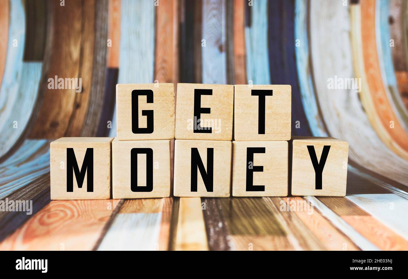 Holzblöcke mit dem Text bekommen Geld auf einem gestreiften Hintergrund Stockfoto