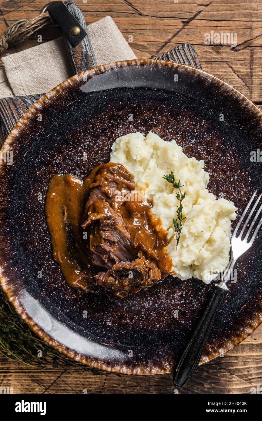 Rinderbacken in Rotweinsauce mit Kartoffelpüree geschmort. Holzhintergrund. Draufsicht Stockfoto