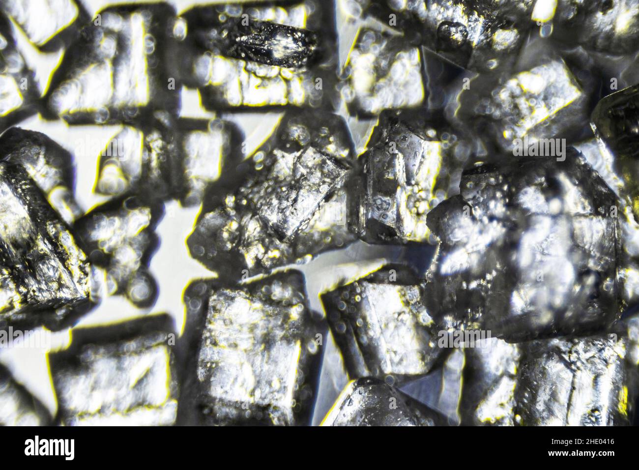 Kristallzucker Nahaufnahme auf weißem Hintergrund unter dem Lichtmikroskop mit einer Vergrößerung von 40-facher Vergrößerung Stockfoto