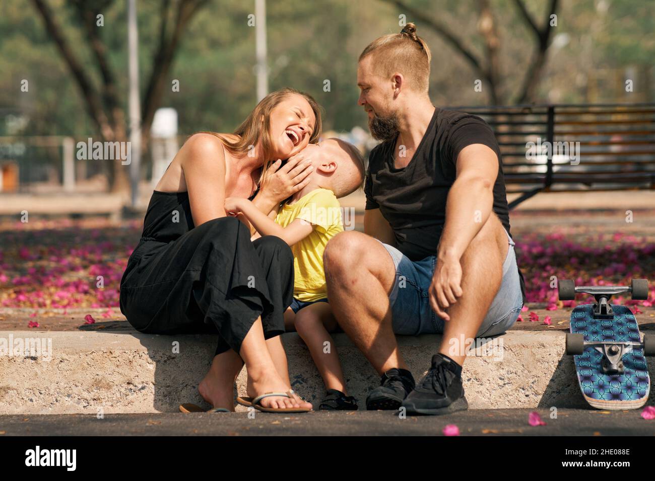 Vater Mutter umarmt ihren kleinen Sohn, während sie im Skatepark sitzt Stockfoto