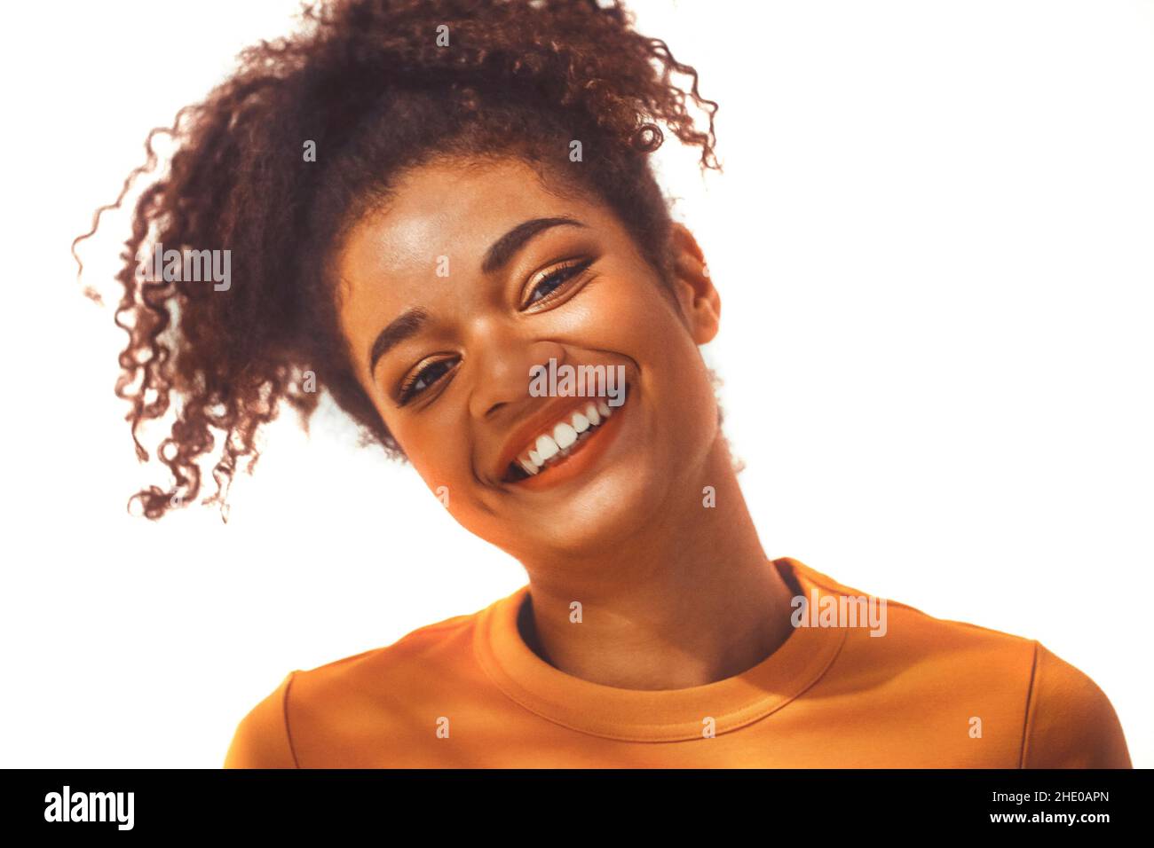 Nahaufnahme Porträt der ruhigen schwarzen afrikanischen jungen Frau mit lockigen üppigen Haaren in hohen Pferdeschwanz gebunden, posiert mit entspannten heiteren Gesichtsausdruck, isola Stockfoto