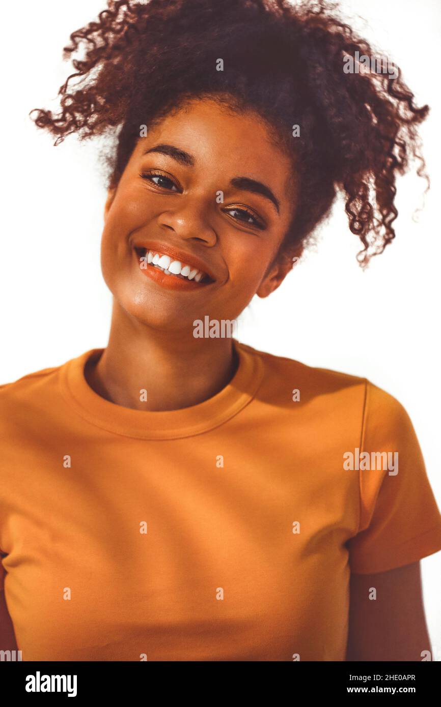 Nahaufnahme Porträt der ruhigen schwarzen afrikanischen jungen Frau mit lockigen üppigen Haaren in hohen Pferdeschwanz gebunden, posiert mit entspannten heiteren Gesichtsausdruck, isola Stockfoto