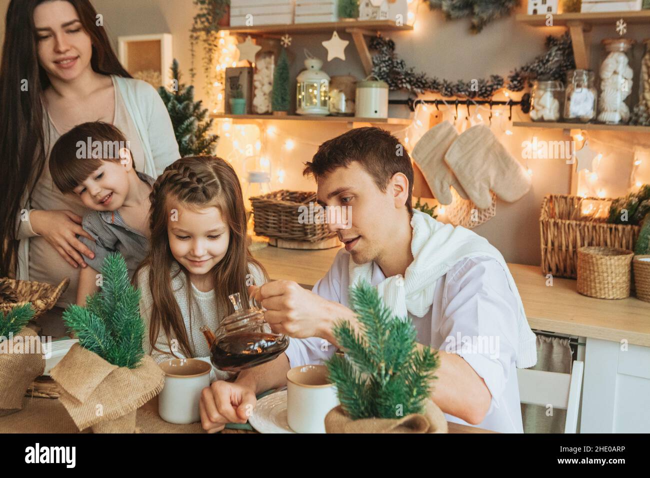 Junge, glückliche europäische Familie mit Kindern, die gemeinsam Weihnachtsferien in gemütlicher Atmosphäre verbringen. Eltern und zwei kleine Kinder Geschwister sitzen ein Stockfoto