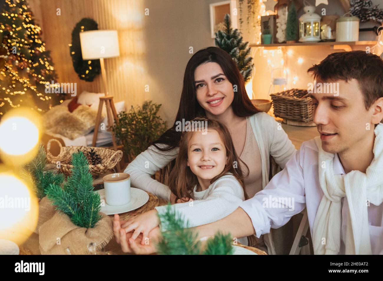 Junge, glückliche europäische Familie mit Kindern, die gemeinsam Weihnachtsferien in gemütlicher Atmosphäre verbringen. Eltern und zwei kleine Kinder Geschwister sitzen ein Stockfoto