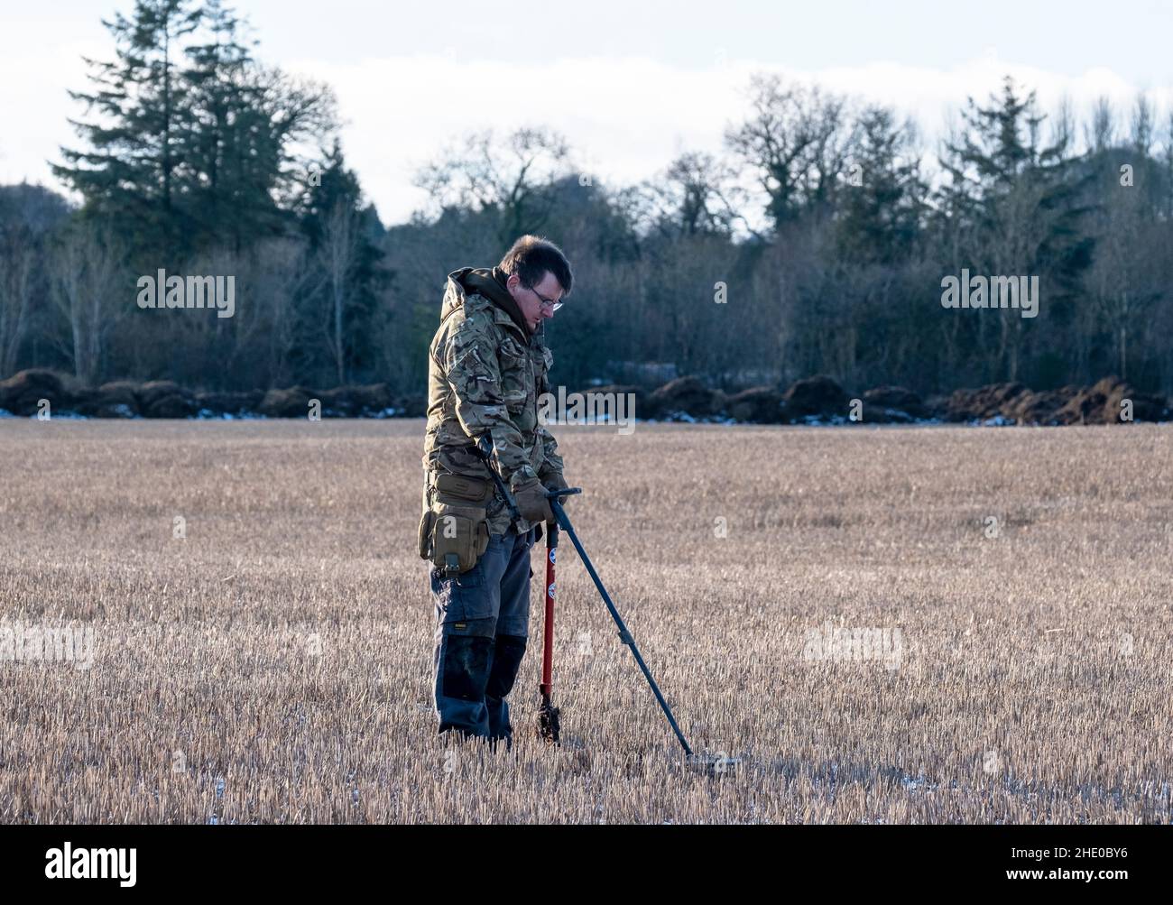 Ein Mann, der Metalldetektor verwendet, um auf einem Bauernfeld in West Lothian, Schottland, nach vergrabenen Münzen zu suchen. Stockfoto