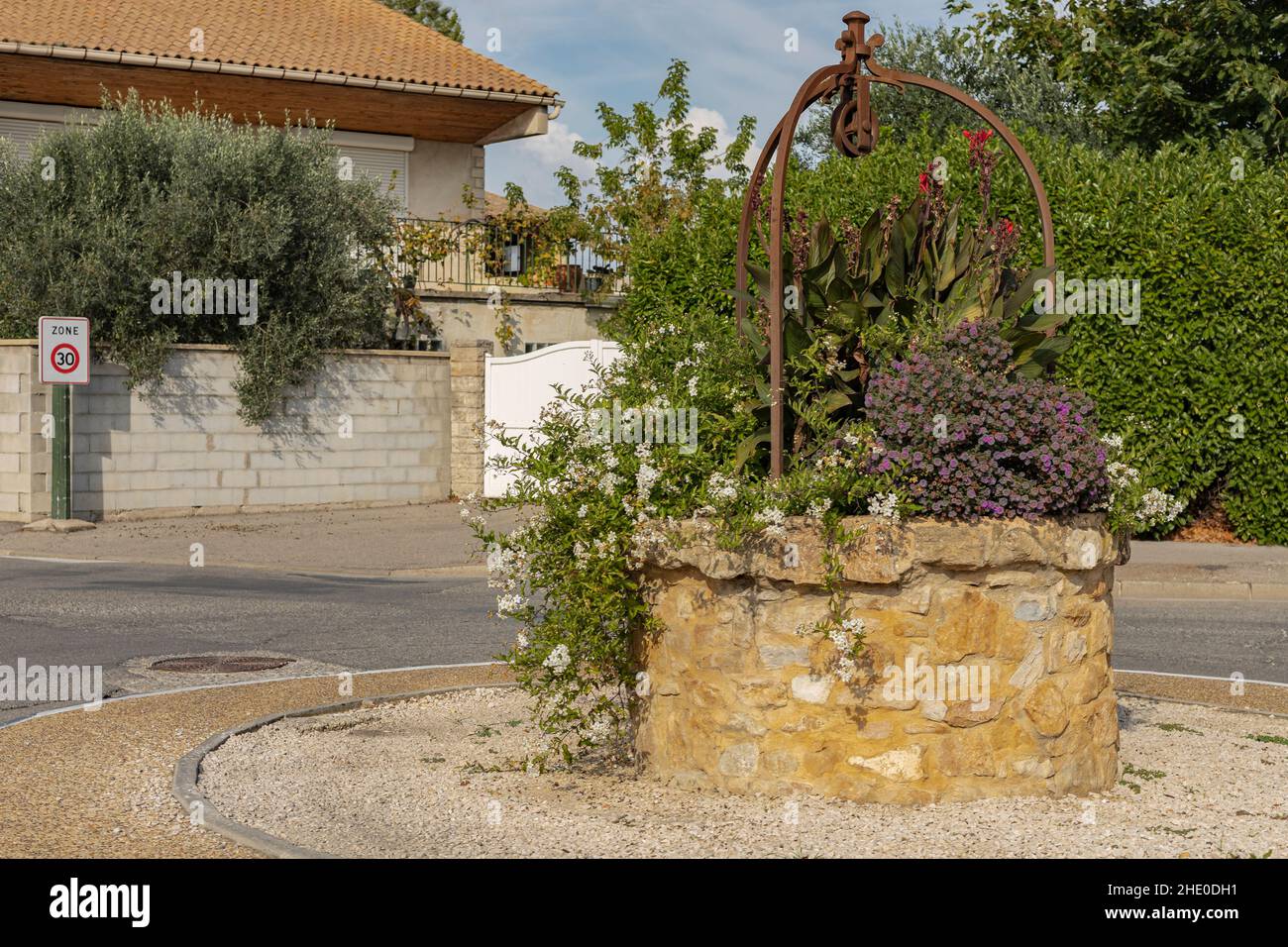 Ein alter Brunnen mit einer Metallplatte in einer Straße, die jetzt zum Blühen verwendet wird Stockfoto