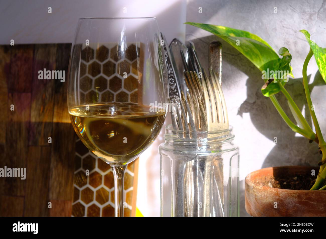 Das natürliche Fensterlicht beleuchtet ein Glas Pinot grigio, das am sonnigen Nachmittag auf einer Marmortheke sitzt Stockfoto