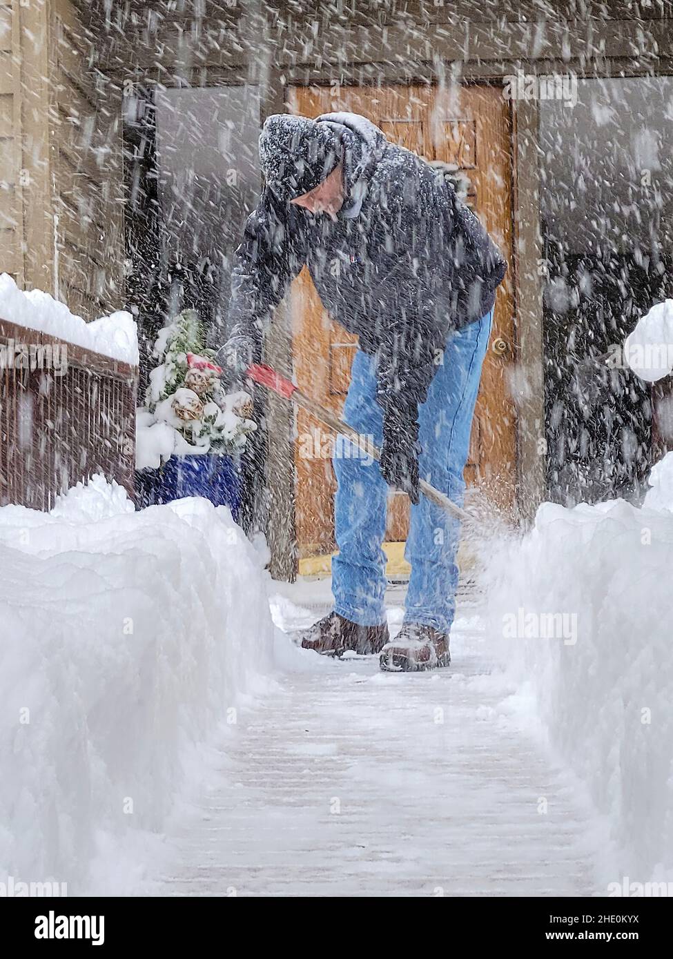 Kaukasischer Mann schaufelt bei einem Schneesturm Schnee Stockfoto