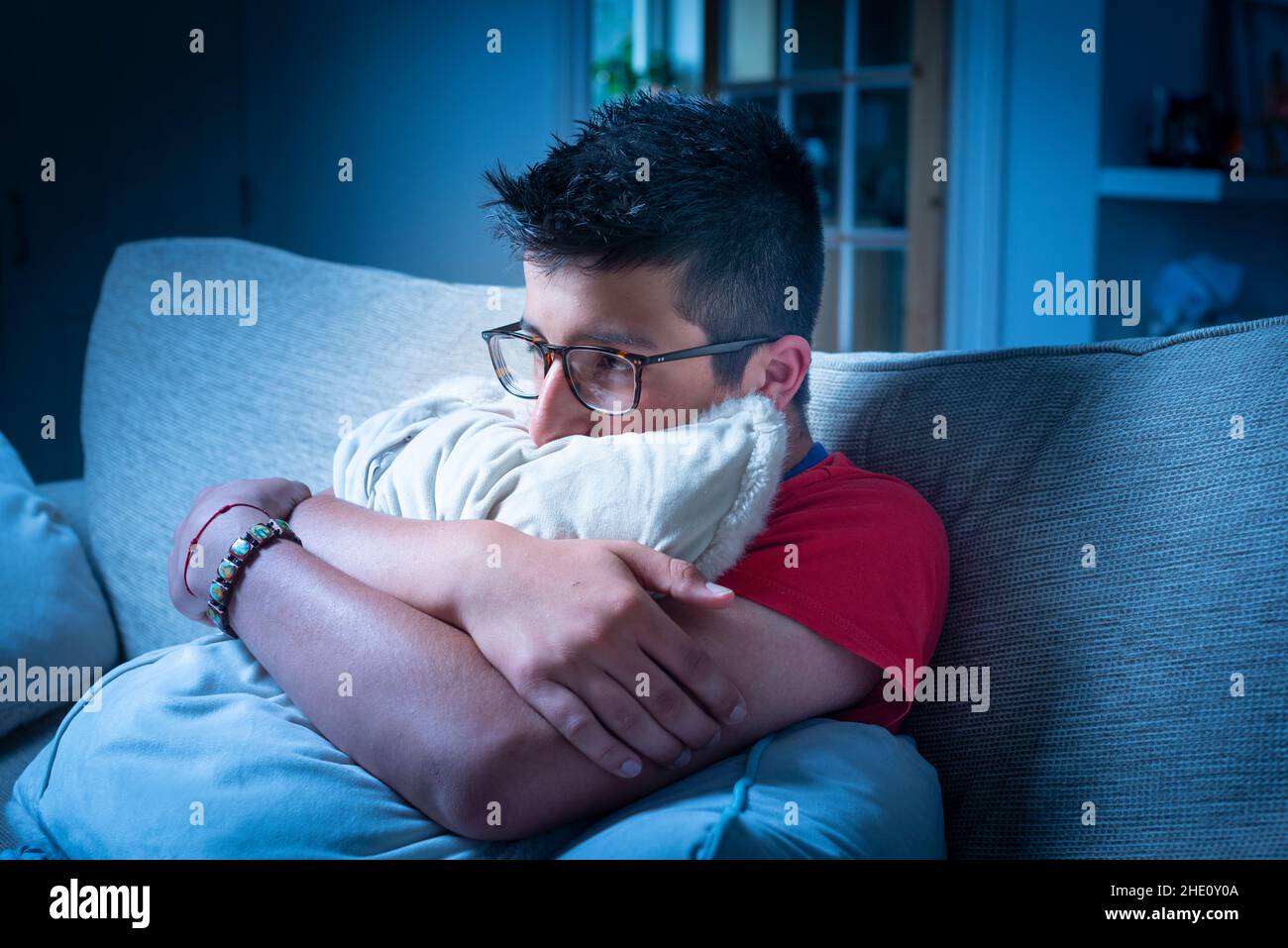 Frustrierte Teenager-Reise 15 Jahre, schaut TV, umarmt ein Kissen. Stockfoto