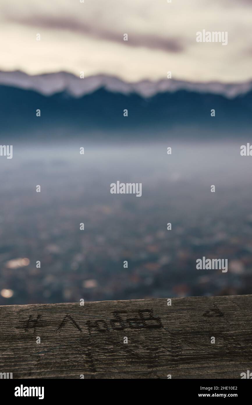 Holzschnitzerei. Übersetzung: Liebe. Im Hintergrund Schneedecke in der Wintersaison. Nebel unter dem Berg Stockfoto