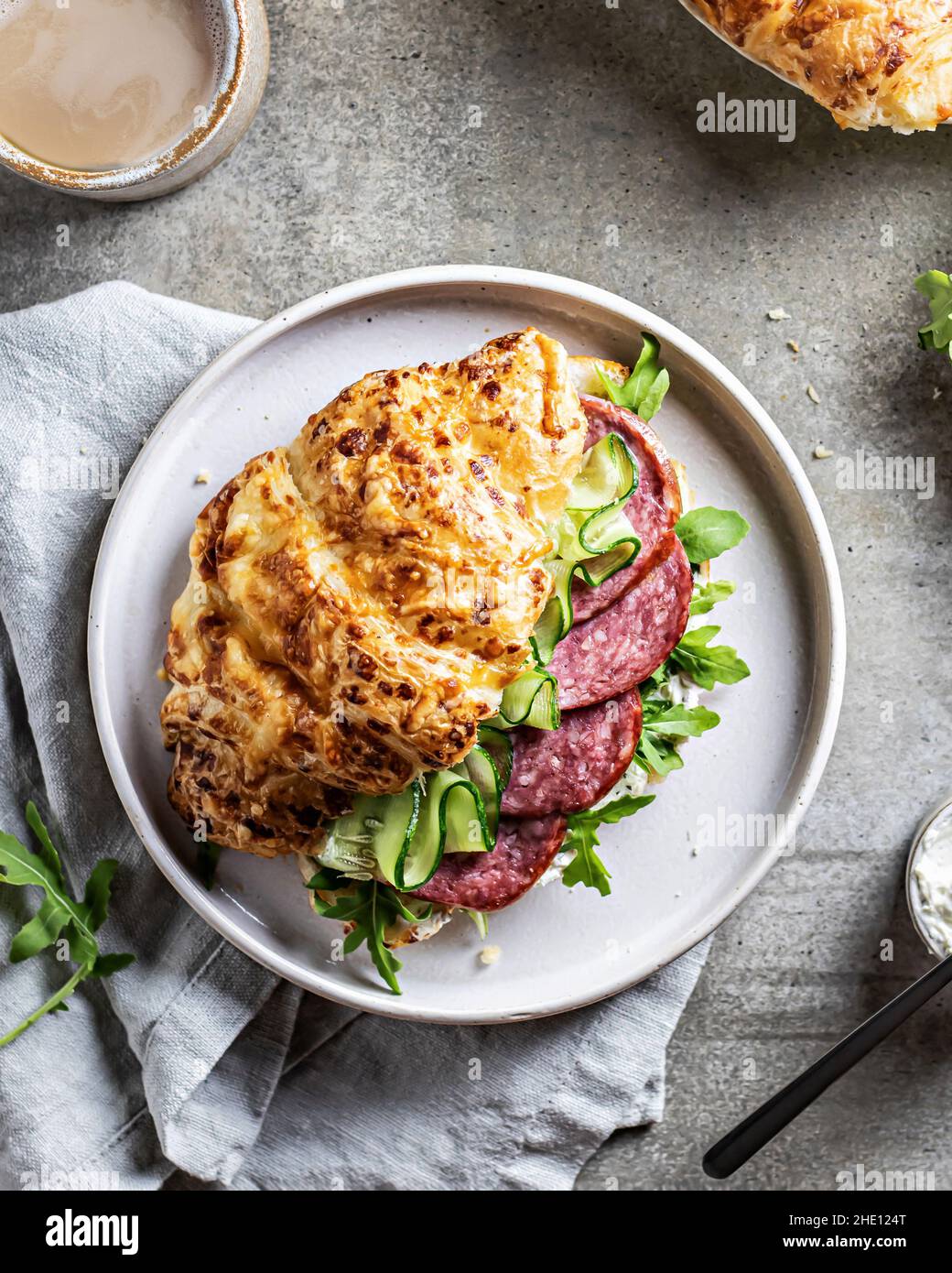 Frisches Croissant-Sandwich mit Schinken und Salatblatt mit Kaffee auf strukturiertem Hintergrund, Draufsicht Stockfoto